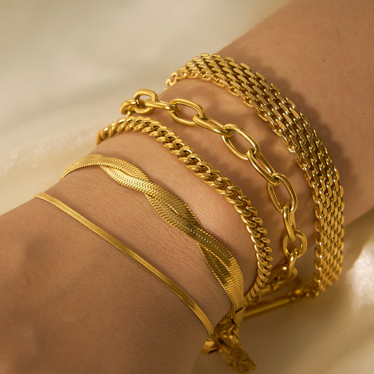 Gold bracelets on a wrist against a neutral background