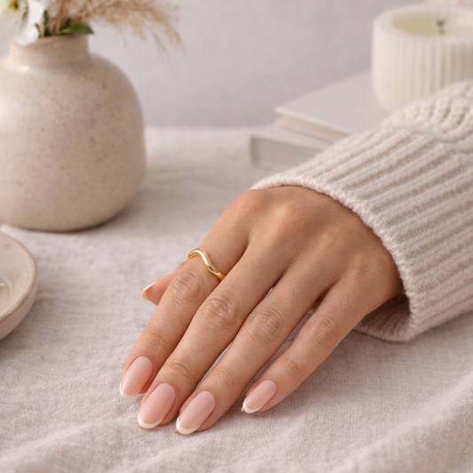 Hand wearing an elegant gold ring with a neutral background