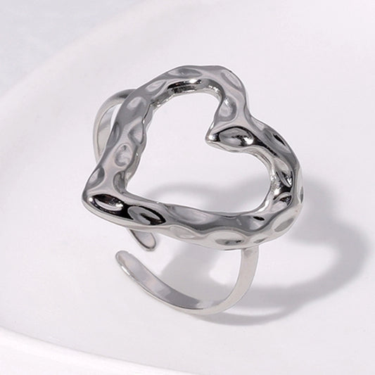 Silver heart-shaped ring on a light gray background