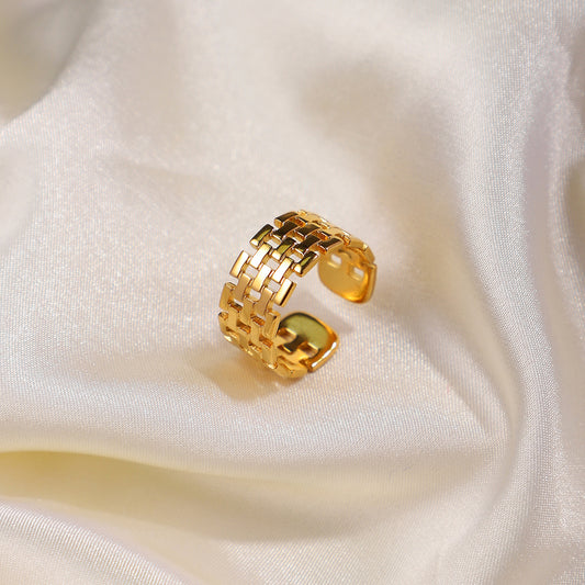 Gold ring with a woven design on a white fabric background