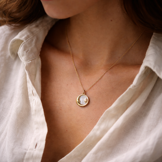 Close-up of a person wearing a delicate gold necklace with a round pendant.