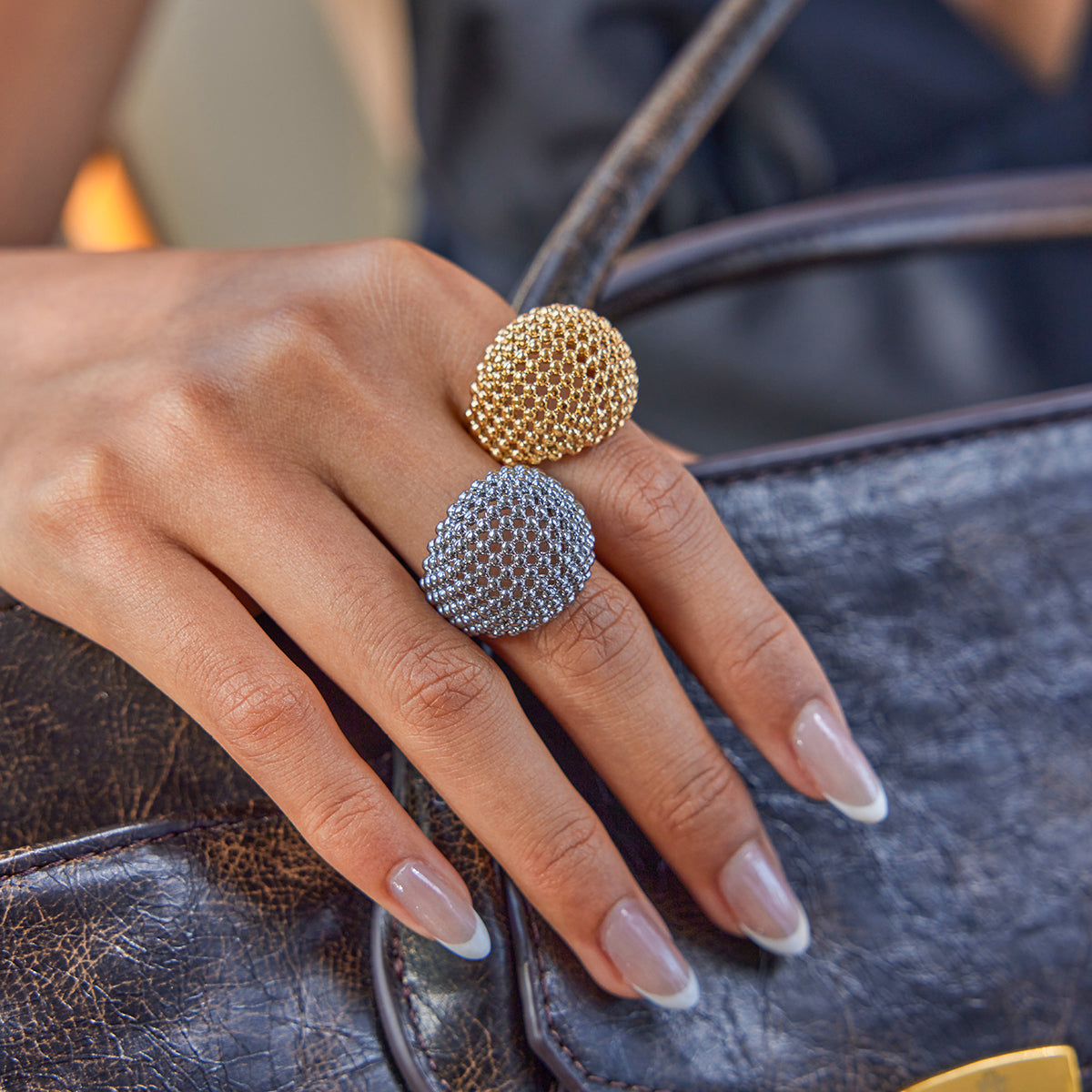 Hand wearing two waterproof rings on a leather surface