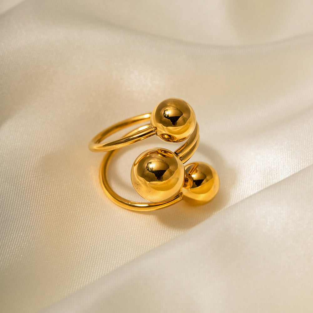 Gold stainless steel ring with spherical design on a beige fabric background
