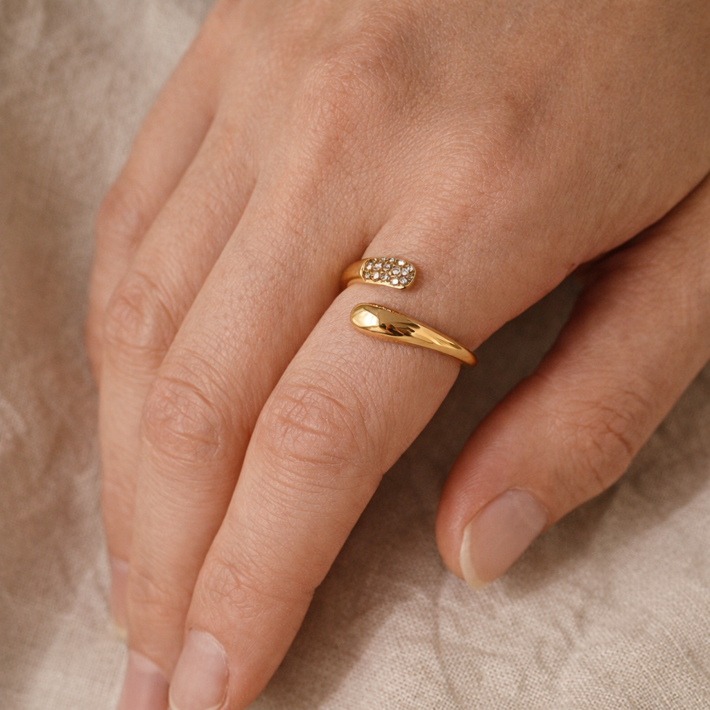 Close-up of a hand wearing two gold rings on a beige background