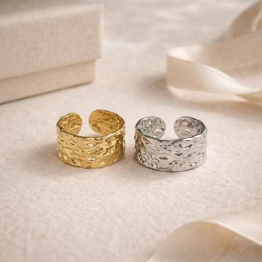 Gold and silver textured rings on a soft fabric background