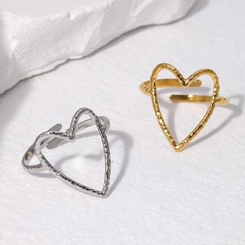 Gold and silver heart-shaped rings on a white fabric background
