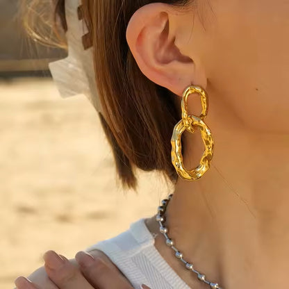 Gold hoop earrings worn by a person with a blurred background