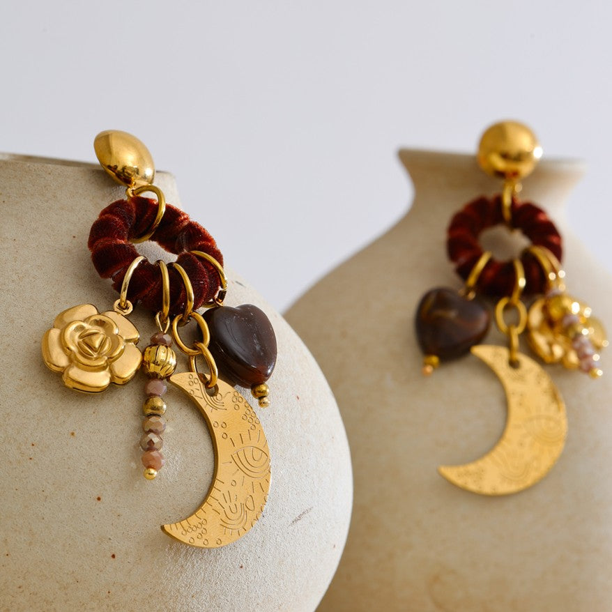 Pair of gold and brown earrings on a textured surface