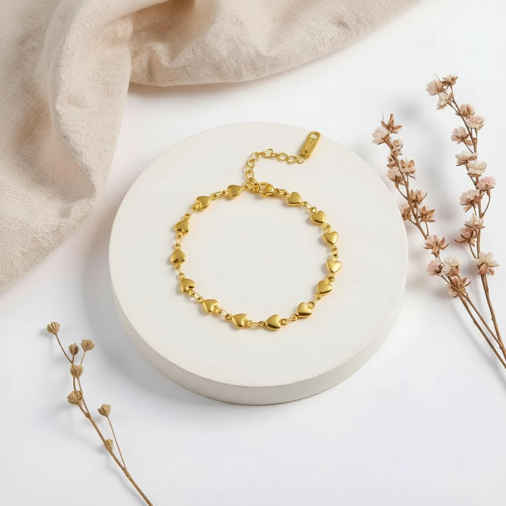 Gold bracelet on a white stone surface with beige fabric and dried flowers