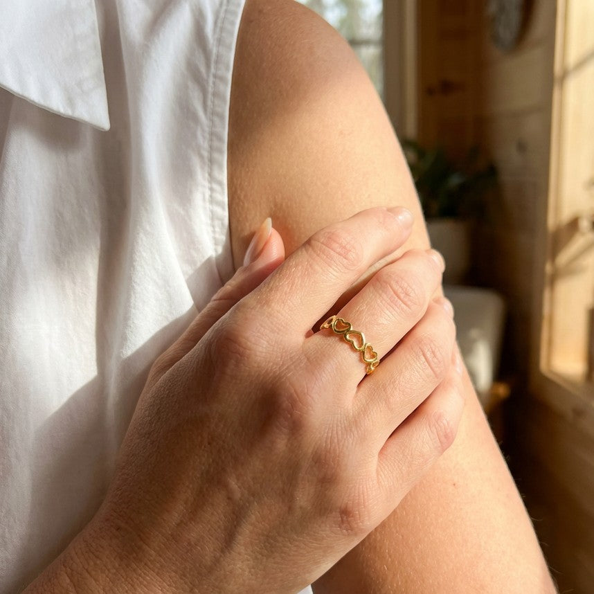 hand wearing a beautiful heart-shaped ring in gold color