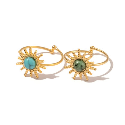 Gold rings with turquoise and green gemstones on a white background