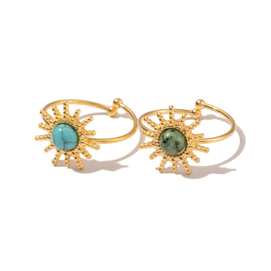 Gold rings with turquoise and green gemstones on a white background