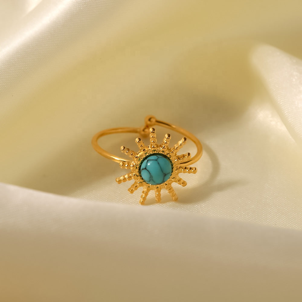 Gold ring with turquoise stone on a beige fabric background