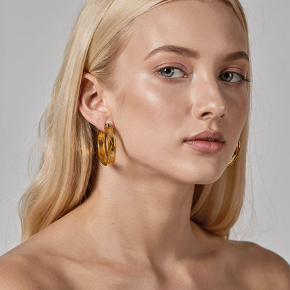 a woman wearing gold statement hoops