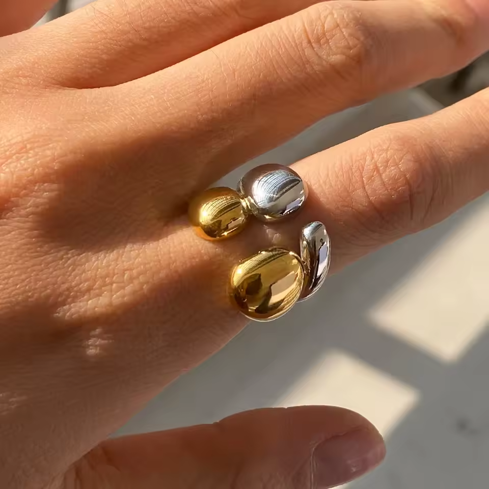 Close-up of a hand wearing two-tone ring on a light background
