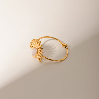 Gold ring with sunflower design on a beige background