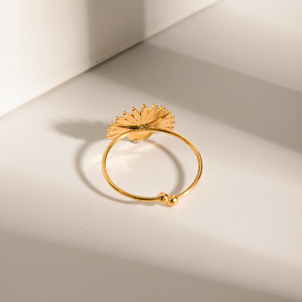 Gold ring with leaf design on a light beige background