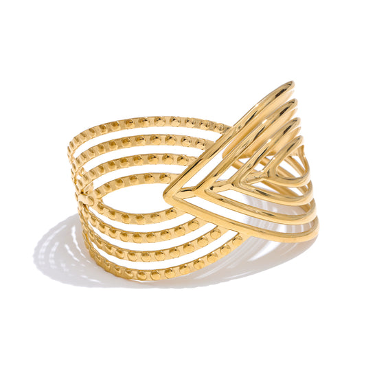 Gold bangle with a unique design on a white background