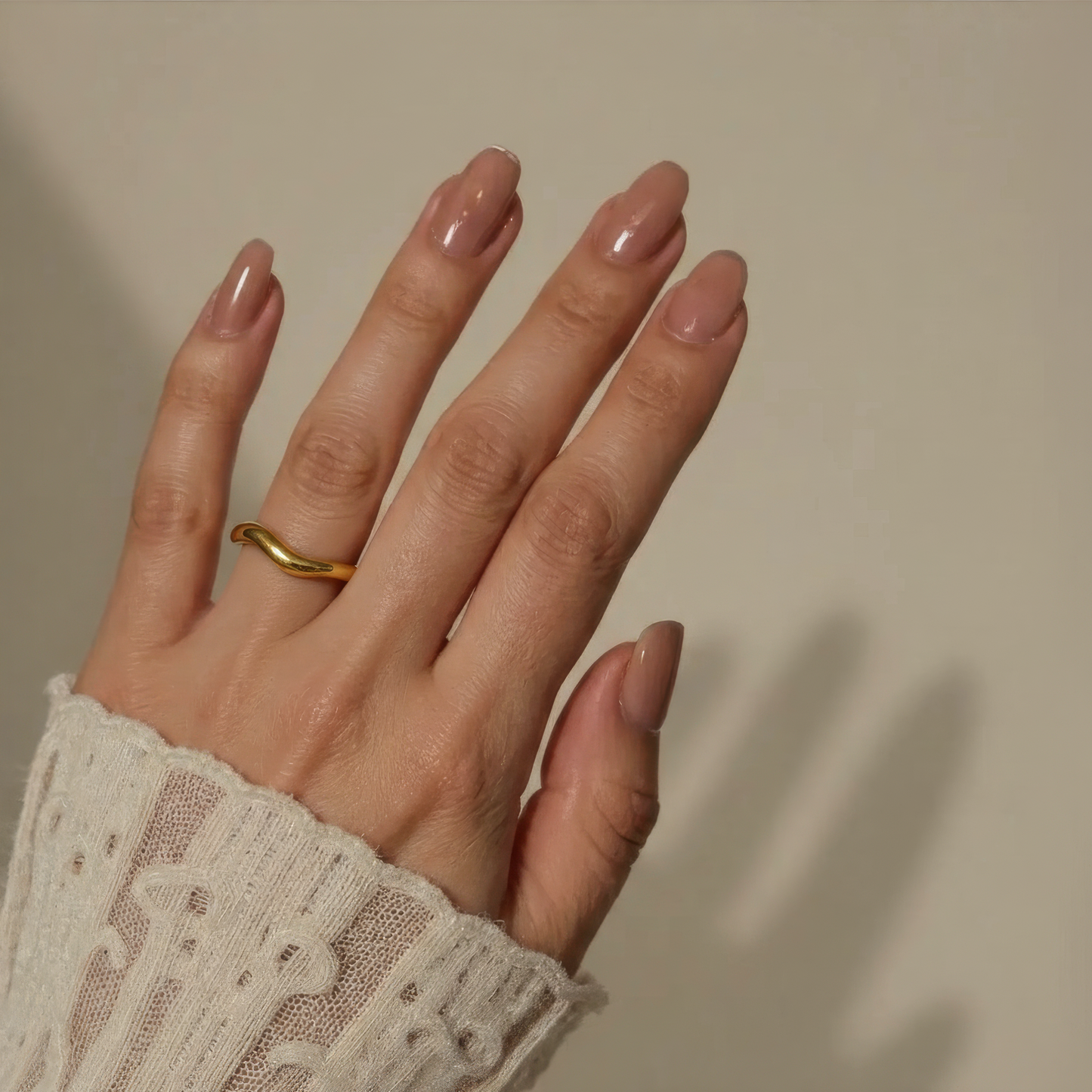 Hand with a gold ring on a neutral background