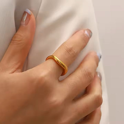 Hand wearing a gold ring with a plain background