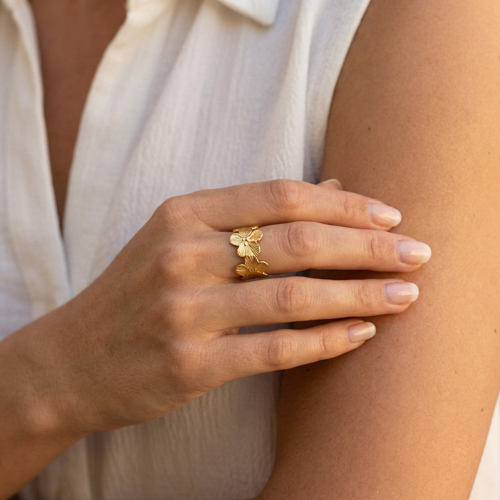 Hand wearing a gold high-quality ring with a floral design on a light background