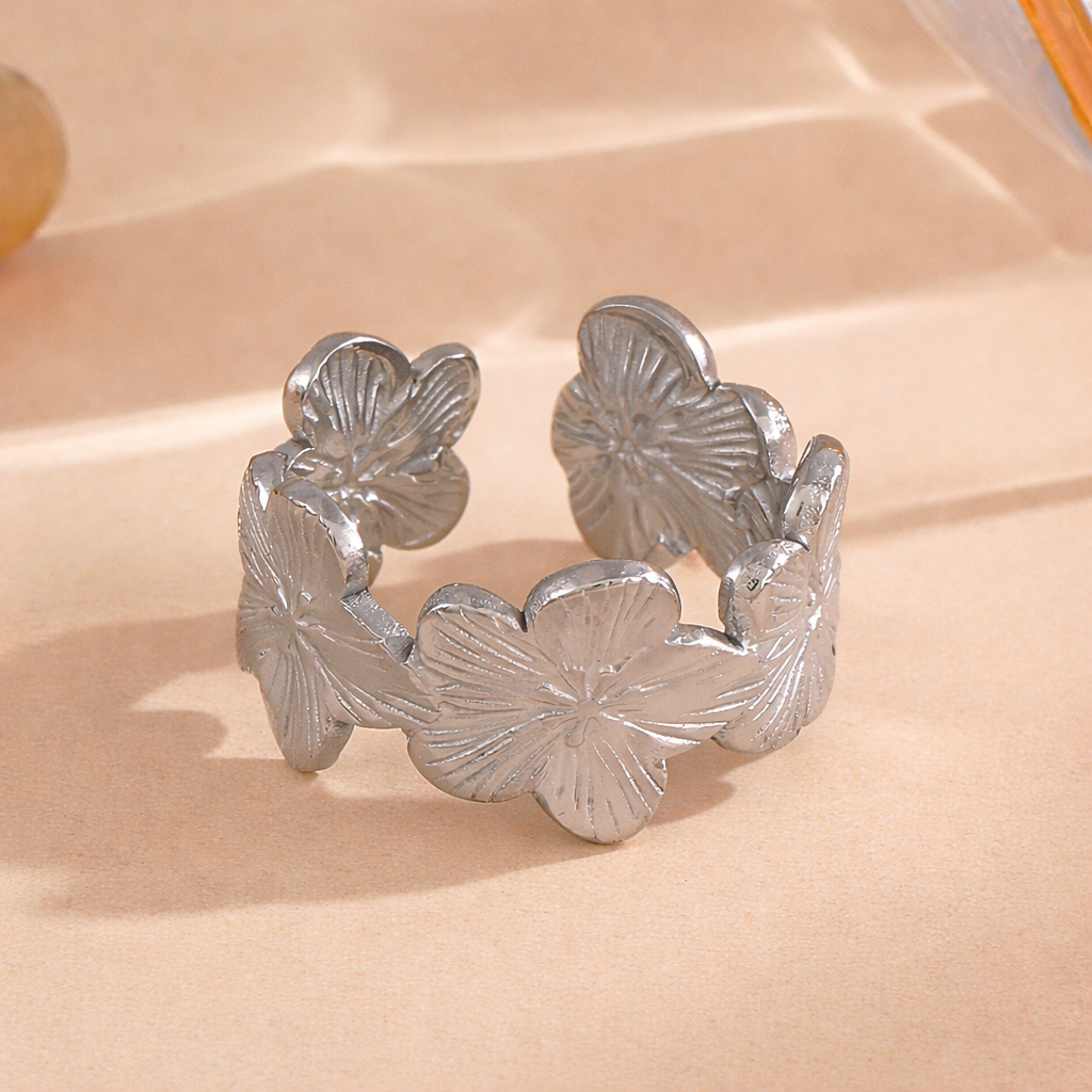 Silver tarnish-free ring with flower designs on a beige surface
