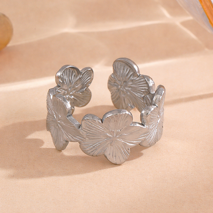 Silver tarnish-free ring with flower designs on a beige surface