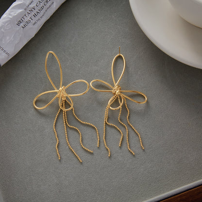 Gold statement earrings on a gray surface with a blurred background