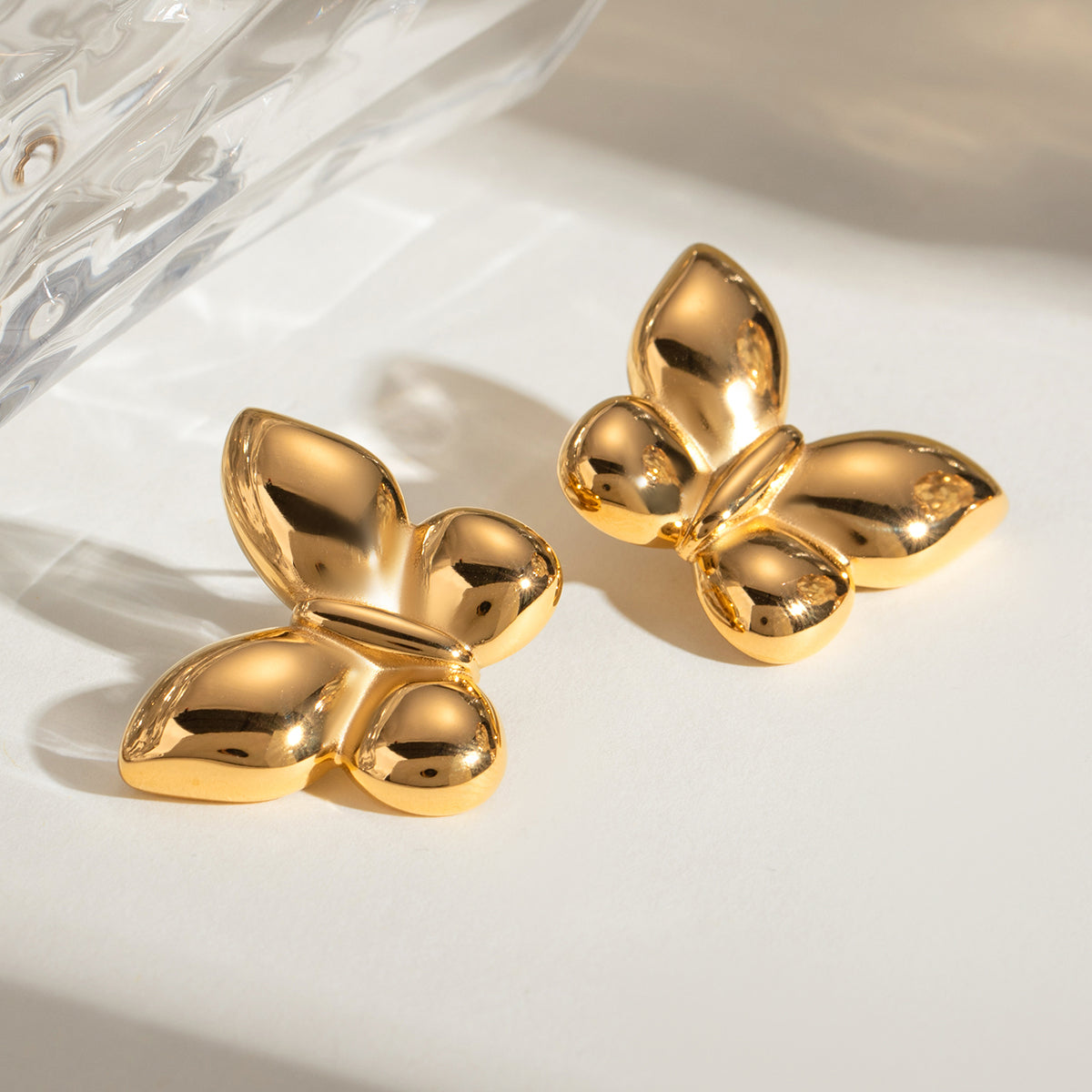 Gold stainless steel butterfly-shaped earrings on a light background