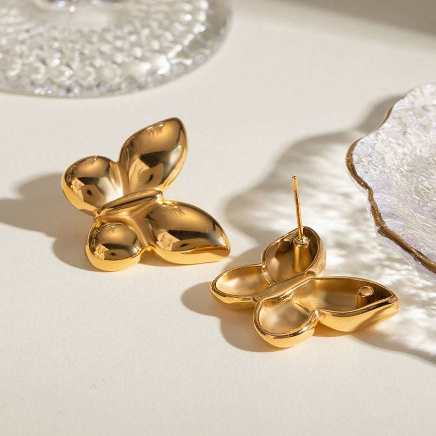Gold butterfly-shaped earrings on a light surface