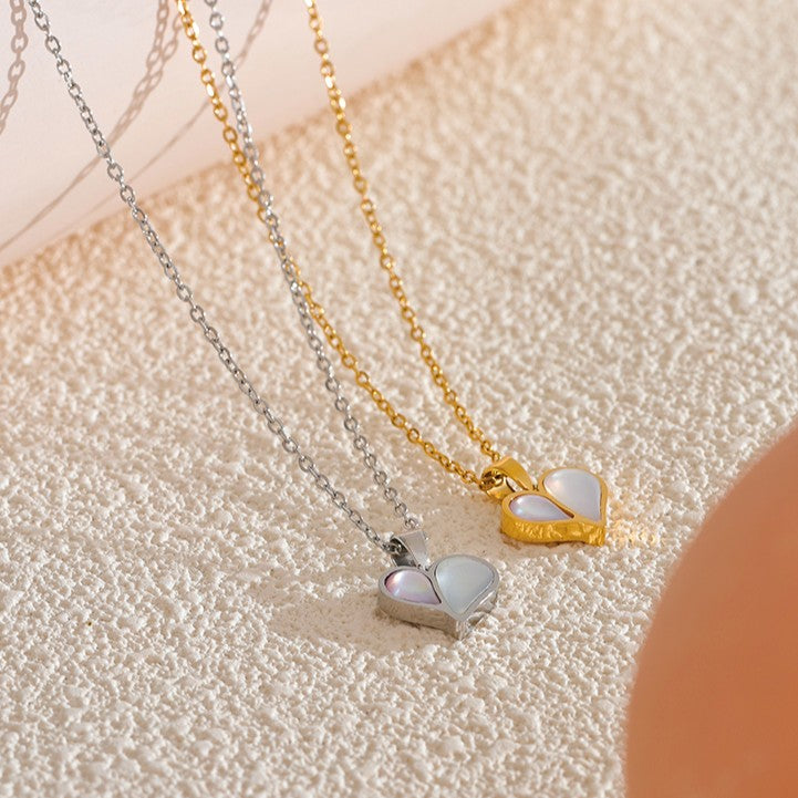 Two heart-shaped pendants on gold and silver chains against a textured beige background