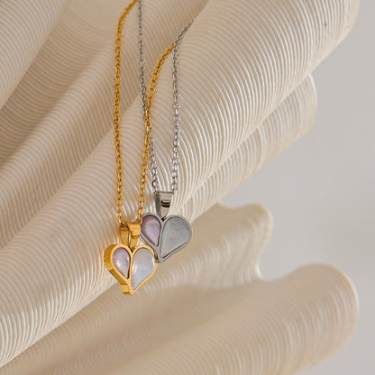 Two heart-shaped pendants on gold and silver chains against a shell background