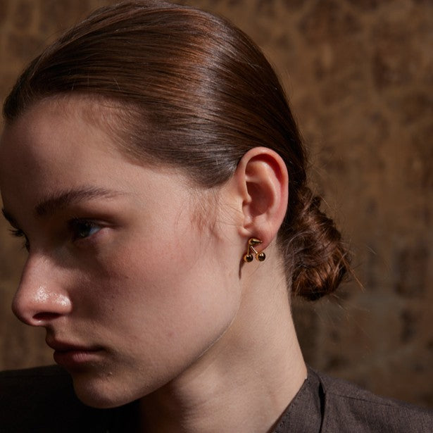 Close-up of a person wearing gold stainless steel earrings with a blurred background