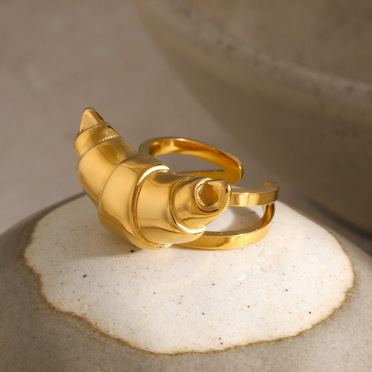 Gold croissant-shaped ring on a textured surface