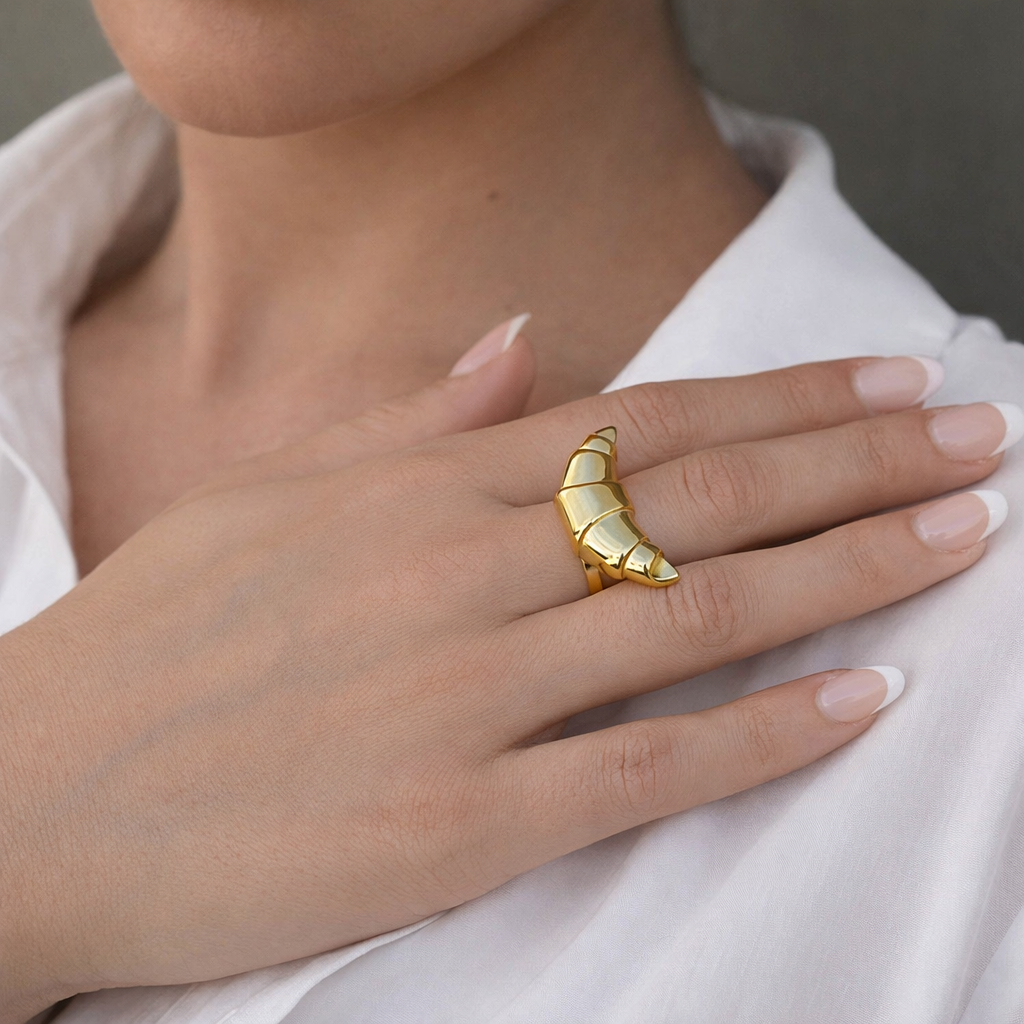 Gold chunky ring on a hand with a neutral background