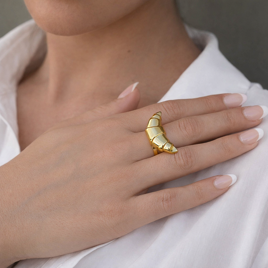 Gold chunky ring on a hand with a neutral background