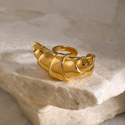 Gold ring with a croissant design on a stone surface