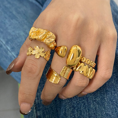 Hand wearing multiple gold rings with a blue denim background