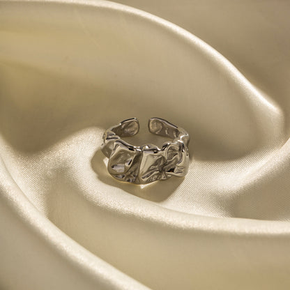 Silver ring on a beige satin surface