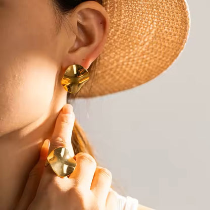 Close-up of a person wearing gold earrings, statement ring and a straw hat.