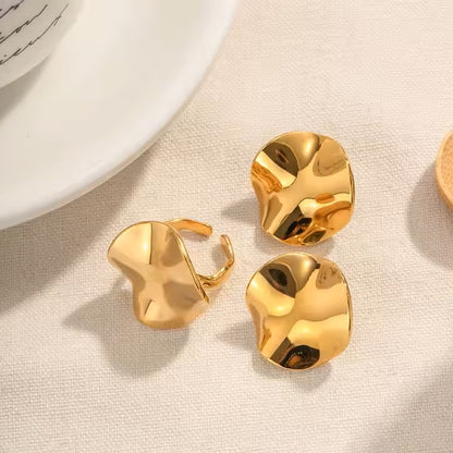 Gold earrings and a gold ring on a beige fabric background