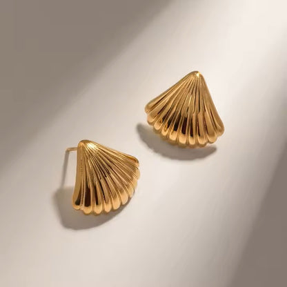 Pair of gold shell-shaped stainless steel earrings on a light background