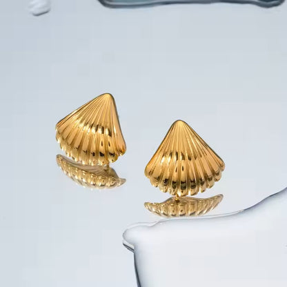 Gold shell-shaped earrings on a light blue background