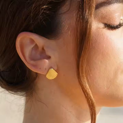 Close-up of a person wearing a gold shell-shaped earring.