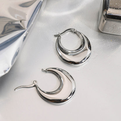 Silver stainless steel hoop earrings on a reflective surface