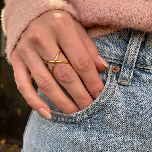 Hand wearing an elegant gold ring with a blurred background