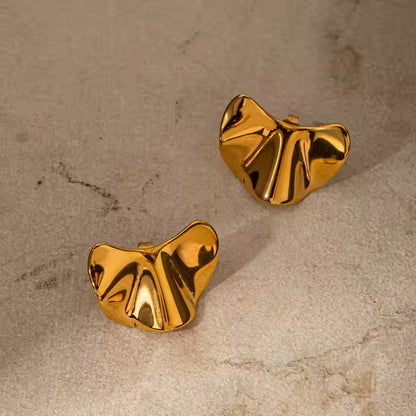 Pair of gold stainless steel earrings on a beige surface