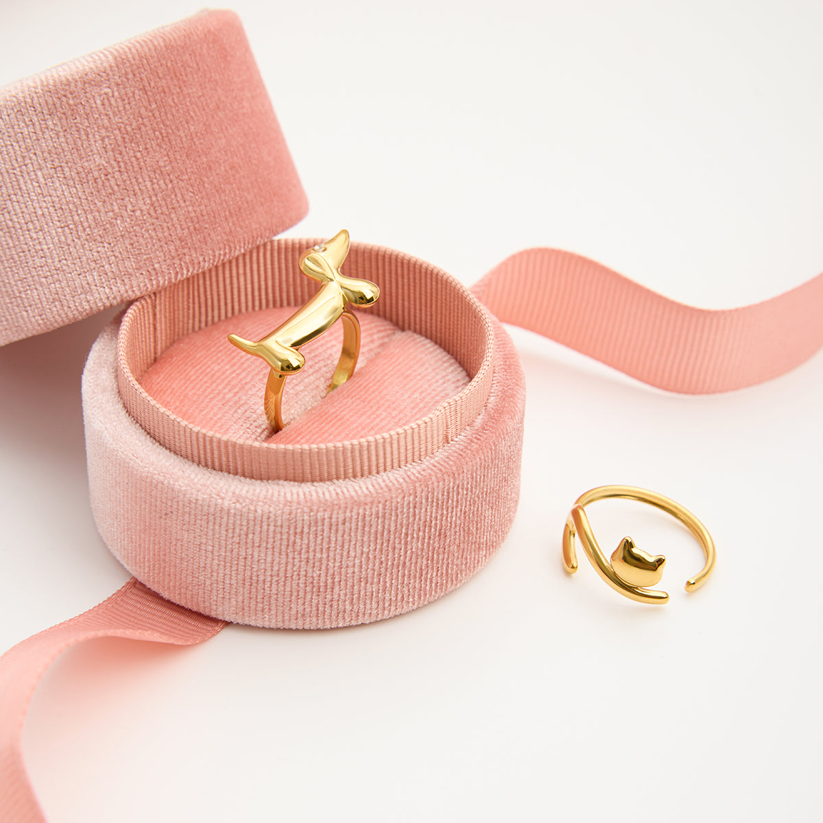 Gold ring in a pink jewelry box with a pink ribbon on a light background