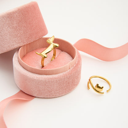 Gold ring in a pink jewelry box with a pink ribbon on a light background