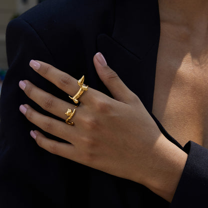 Hand wearing two gold rings with a blurred background
